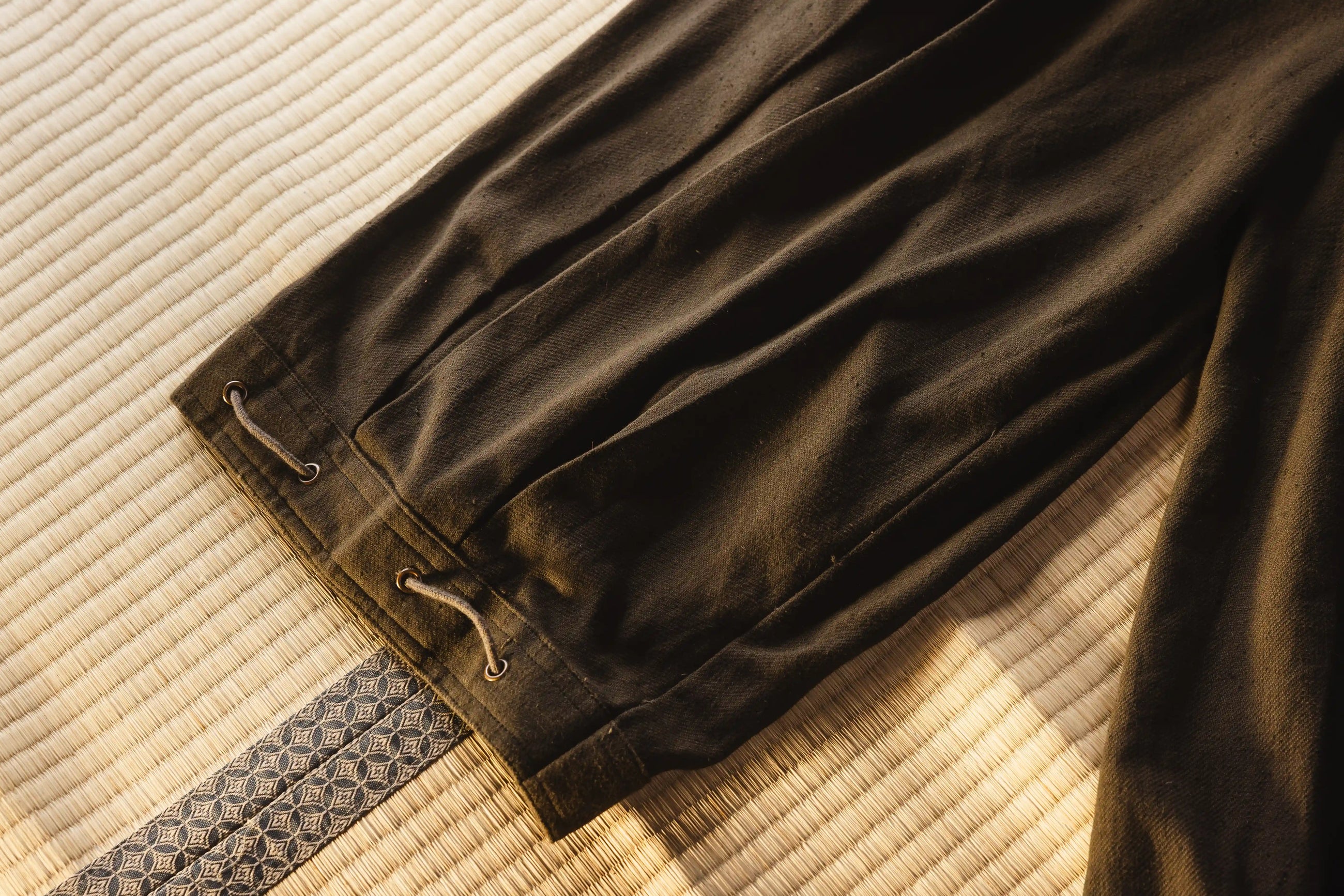 Brown pants with drawstring on a textured beige surface