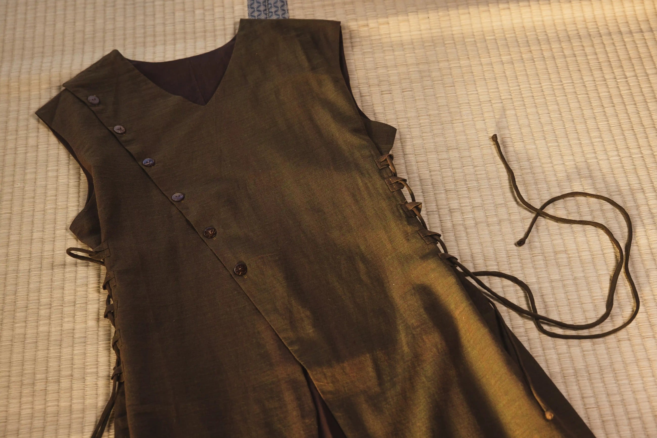 Brown leather vest with buttons and laces on a checkered fabric background