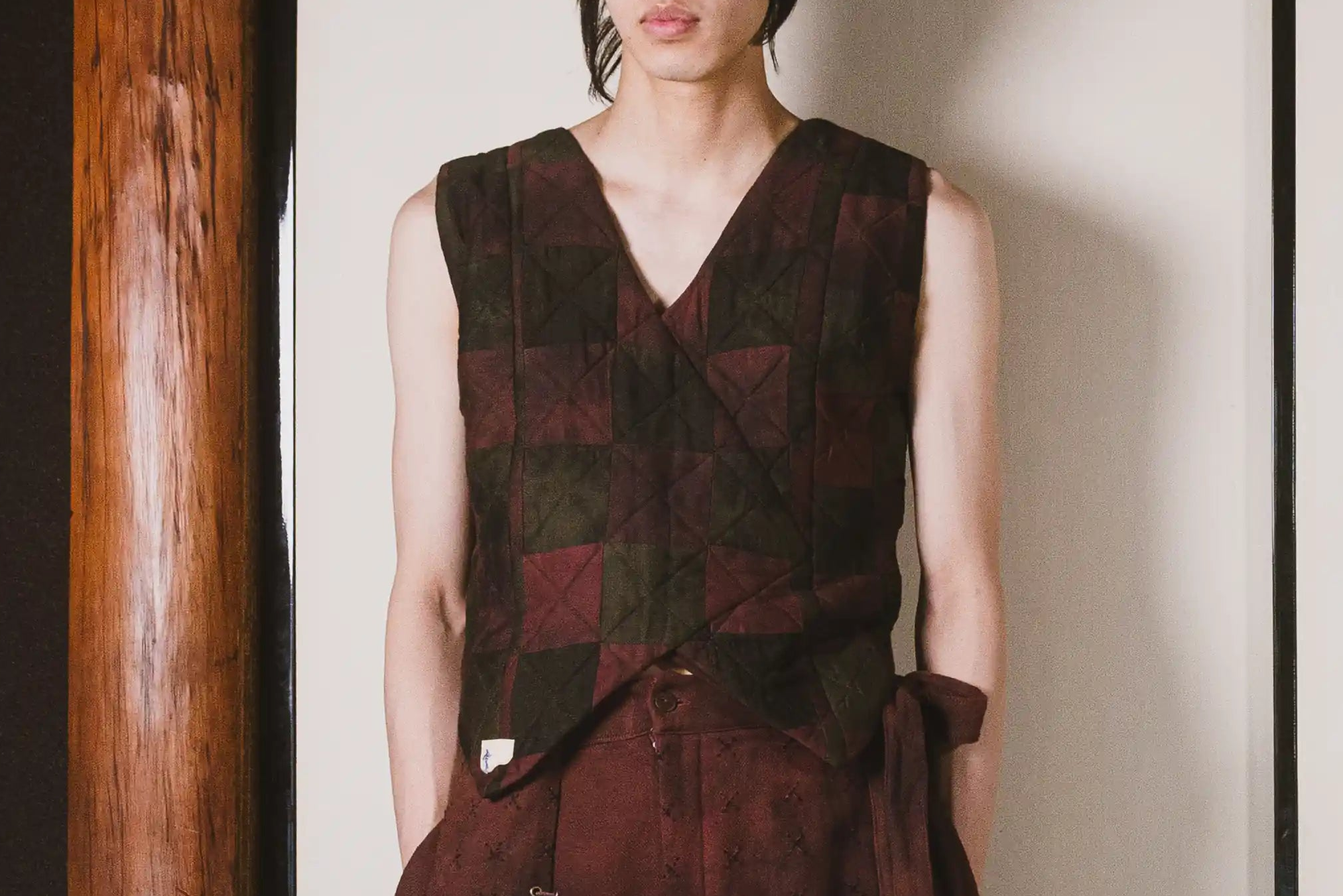 Person wearing a patterned vest against a plain background