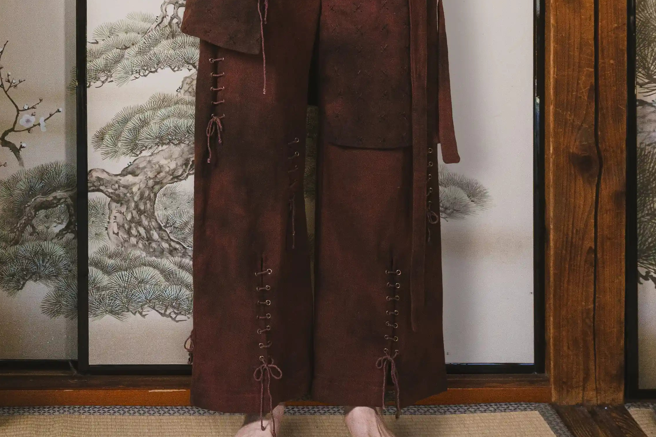 Brown traditional outfit with a wooden screen and tree design in the background