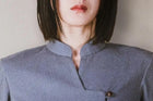 Person wearing a textured blue shirt with a plain background