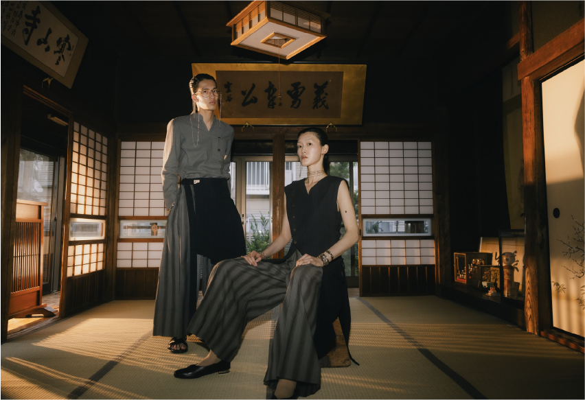 Three people in traditional attire in a Japanese-style room with wooden floors and sliding doors.