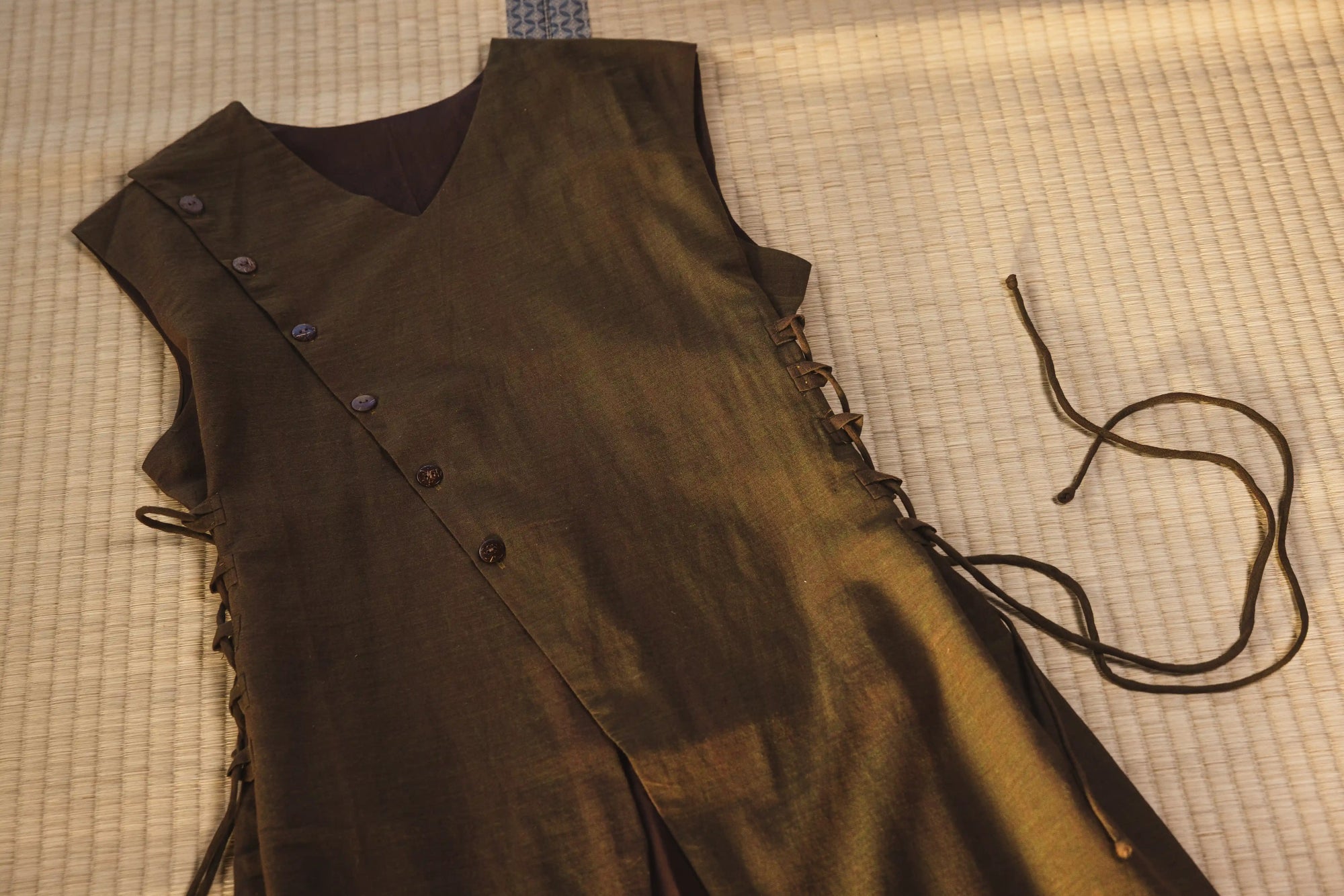 Brown leather vest with buttons and laces on a checkered fabric background