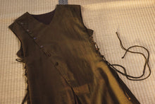 Brown leather vest with buttons and laces on a checkered fabric background