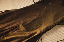 Brown leather dress with fringes on a textured surface