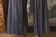 Traditional Japanese kimono worn by a person in a room with wooden elements and a painting.