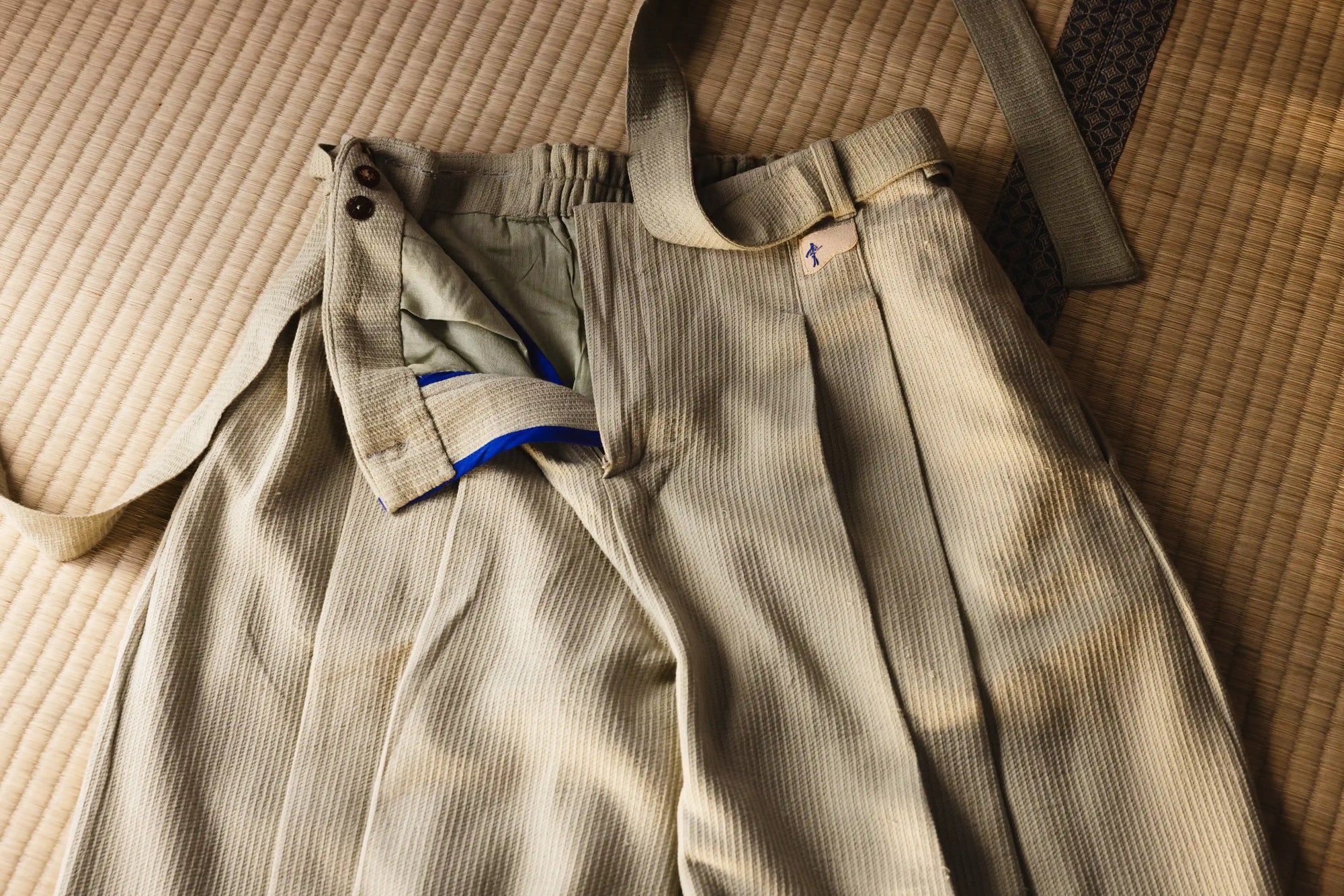 Beige corduroy pants with suspenders on a textured surface