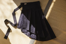 Black pleated skirt with a belt on a textured surface