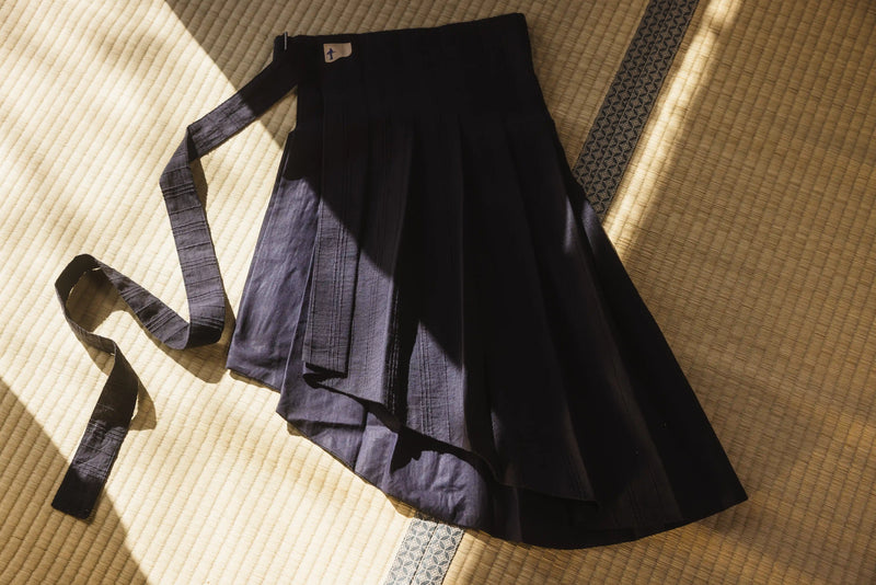 Black pleated skirt with a belt on a textured surface