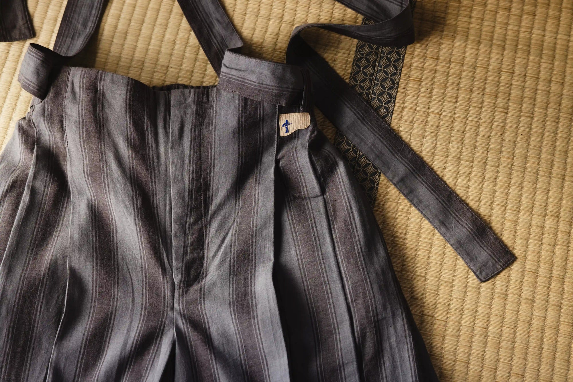 Gray martial arts uniform with a black belt on a tatami mat