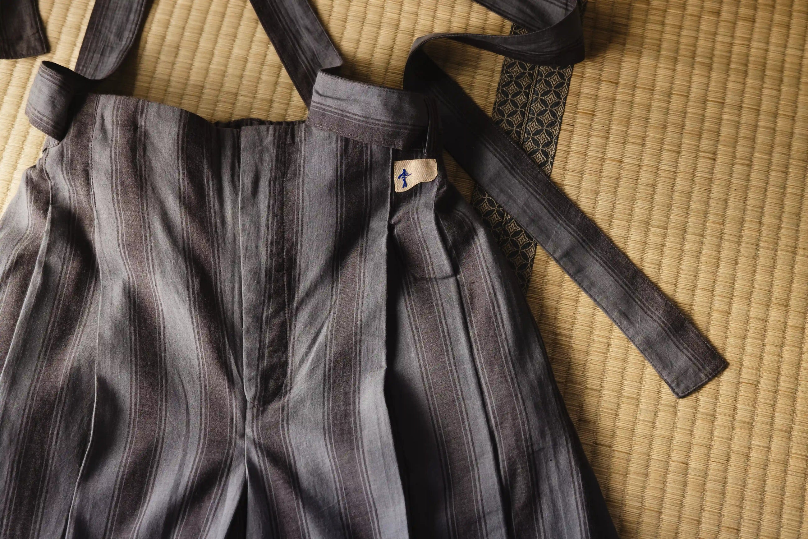 Gray martial arts uniform with a black belt on a tatami mat
