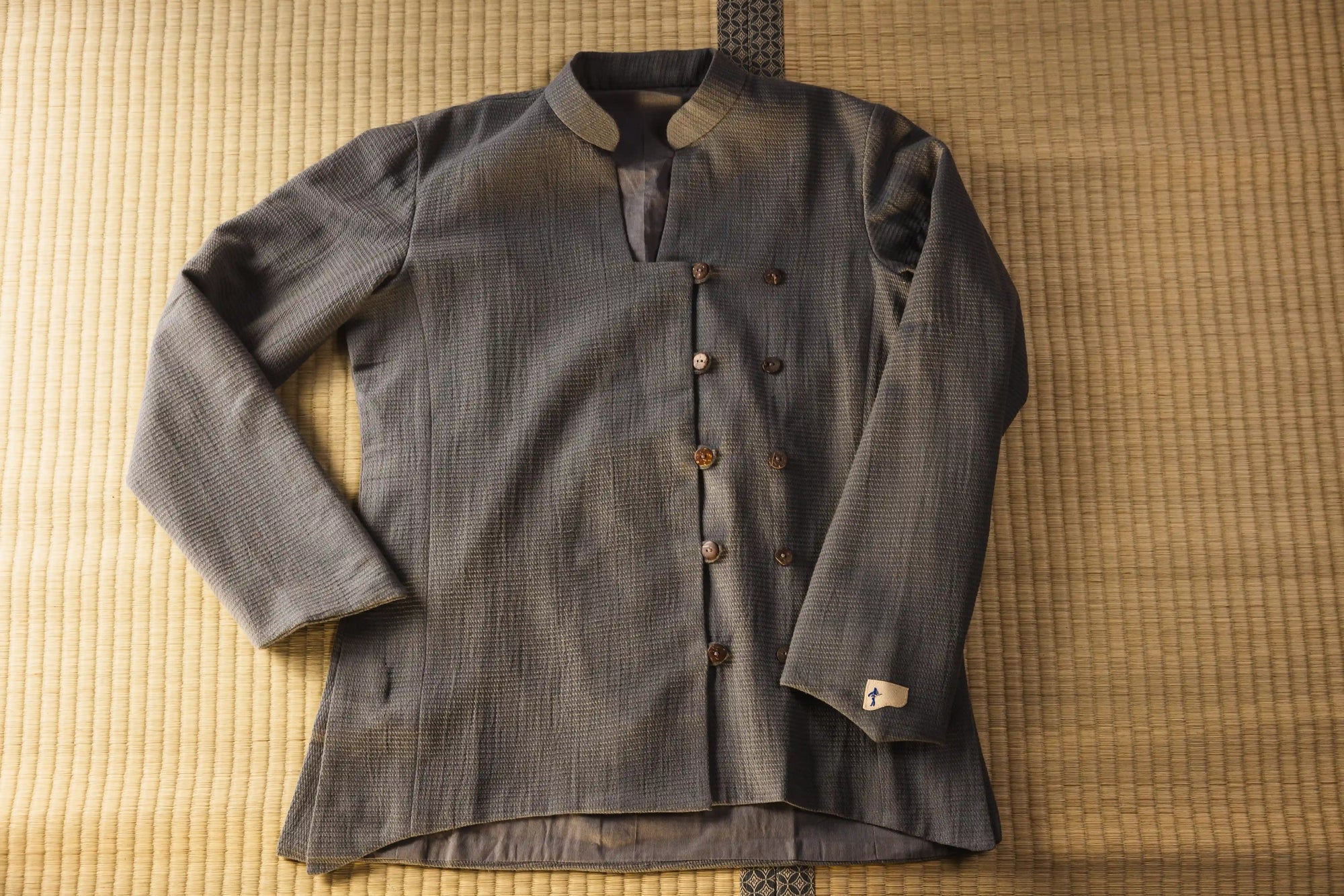 Vintage-style gray jacket with brown buttons on a textured surface