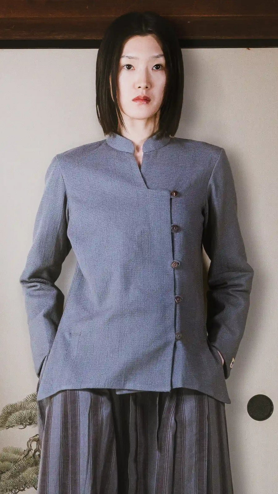 Woman wearing a gray traditional jacket against a plain background