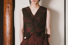 Person wearing a patterned vest against a plain background