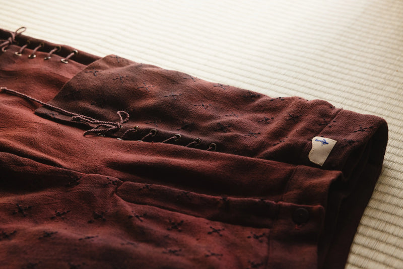Brown pants with a tag on a light-colored surface