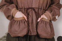 Brown garment with puffed sleeves and a belt on a neutral background