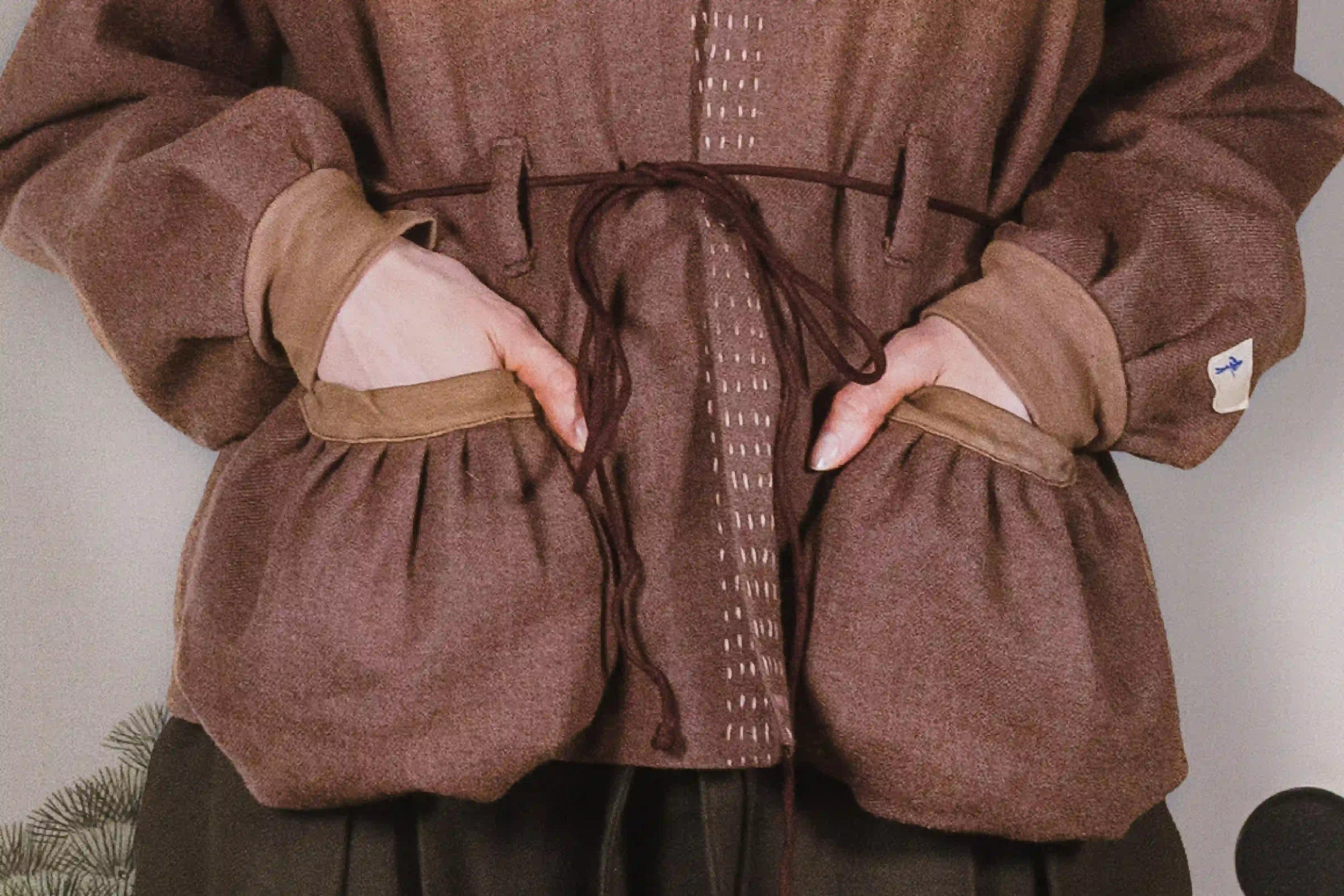 Brown garment with puffed sleeves and a belt on a neutral background
