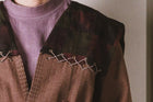 Close-up of a brown garment with decorative buttons on a plain background